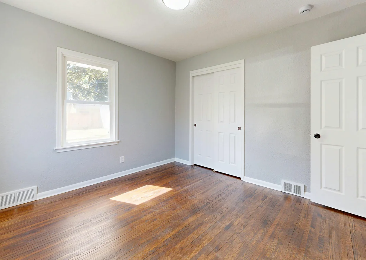 Spacious empty room with hardwood floors and sunlight streaming through the window in Denver