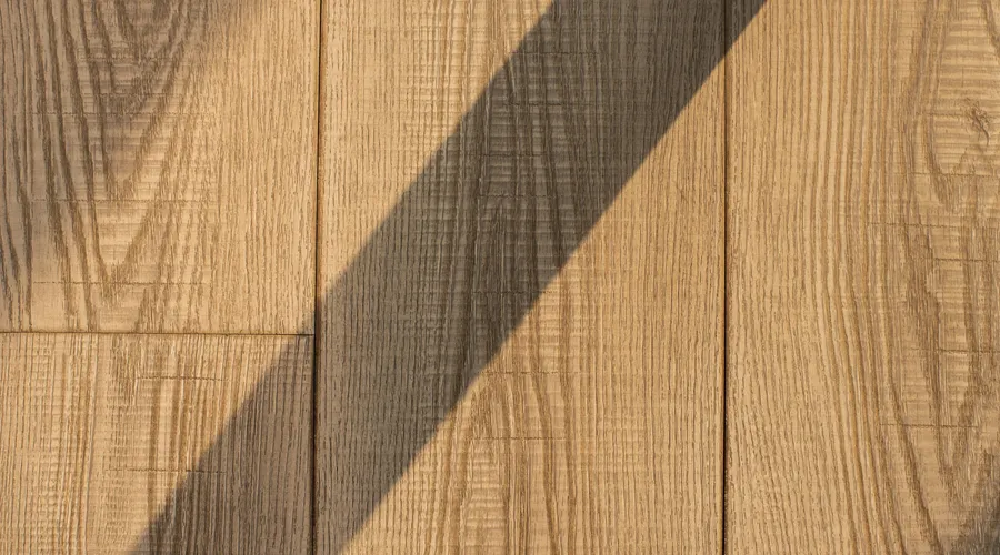 Head-to-Head: Appearance by Wood Type - Detailed view of wooden floor planks with a dramatic shadow