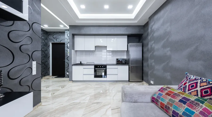 How Long Does It Take? - Kitchen area with white furniture placed near living room with comfortable sofa and TV in contemporary apartment with gray walls