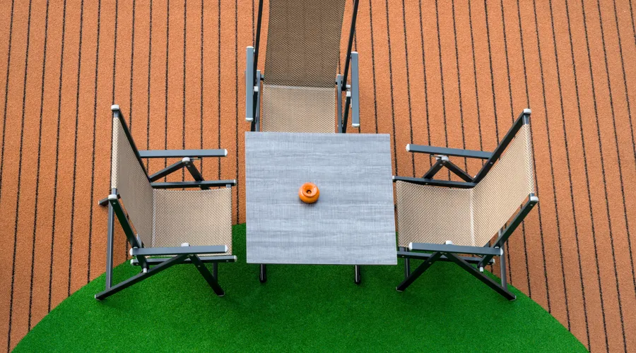 Types of Composite Deck Sealers - Top view of a modern patio furniture set with three chairs and a table on artificial grass