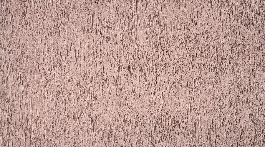 What Is Lime Plaster? - Detailed close-up view of a rough textured brown wall showcasing its unique pattern