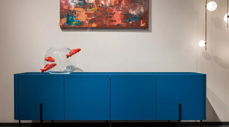 10 Best Paint Colors for Furniture - Modern blue cupboard with glass aquarium decorated with fish placed at white wall with creative picture in modern room with glowing lamps