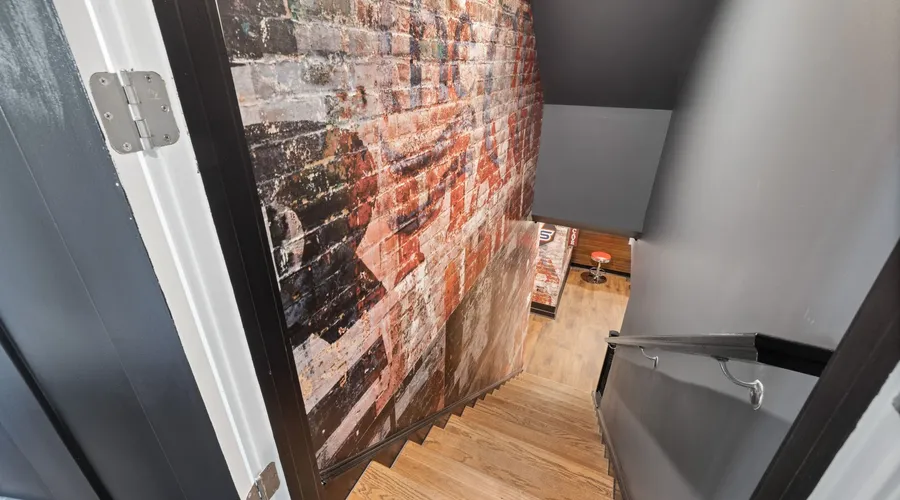 What Is French Wash? - A modern staircase with exposed brick wall art leading to a stylish basement